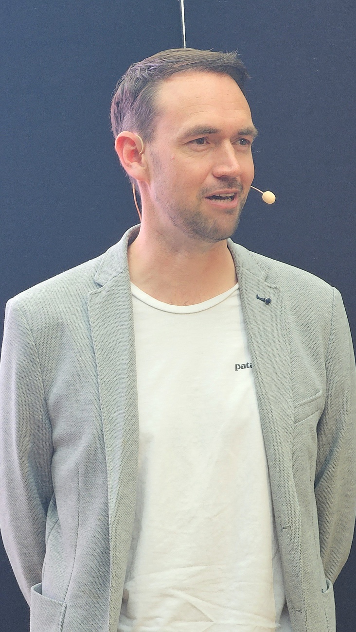 Prof. Niklas Kühl: Einordnung der KI-Entwicklung auf dem KI-Zukunftstag

Mit seiner Keynote "KI: Wo sind wir gerade?" setzte Prof. Niklas Kühl einen der zentralen inhaltlichen Impulse auf dem KI-Zukunftstag in Bayreuth. Als Inhaber des Lehrstuhls für Wirtschaftsinformatik und humanzentrische Künstliche Intelligenz an der Universität Bayreuth zählt er zu den ausgewiesenen Experten im Bereich moderner KI-Anwendungen.

In seinem Vortrag gelang es Prof. Kühl, den aktuellen Stand der Künstlichen Intelligenz verständlich und zugleich fundiert einzuordnen. Dabei spannte er den Bogen von den Entwicklungen der vergangenen Jahre bis hin zu den zukünftigen Potenzialen und Herausf o r d e r ungen für Unternehmen. Besonders deutlich wurde: KI ist längst in der Praxis angekommen und entwickelt sich zunehmend zu einem entscheidenden Wettbewerbsvorteil.

Seine wissenschaftliche Arbeit konzentriert sich auf die Verbindung von technischer KI-Entwicklung und menschzentrierten Ansätzen. Dabei erforscht er unter anderem, wie Menschen und KI effektiv zusammenarbeiten, wie Vertrauen in KI-Systeme entsteht und wie diese fair und verantwortungsvoll eingesetzt werden können.

Durch diese Perspektive gelang es ihm auch in Bayreuth, nicht nur technologische Trends zu beleuchten, sondern vor allem deren konkrete Bedeutung für Unternehmen und Gesellschaft herauszustellen.

Die Teilnehmenden profitierten besonders von der klaren Struktur seines Vortrags und der verständlichen Aufbereitung komplexer Inhalte. Prof. Kühl machte deutlich, dass sich Unternehmen jetzt aktiv mit KI auseinandersetzen müssen, um die Chancen gezielt zu nutzen und gleichzeitig Risiken zu verstehen.

Mit seiner Keynote lieferte er damit eine fundierte Orientierung für den weiteren Verlauf der Veranstaltung - und setzte einen starken inhaltlichen Auftakt für den KI-Zukunftstag in Bayreuth.