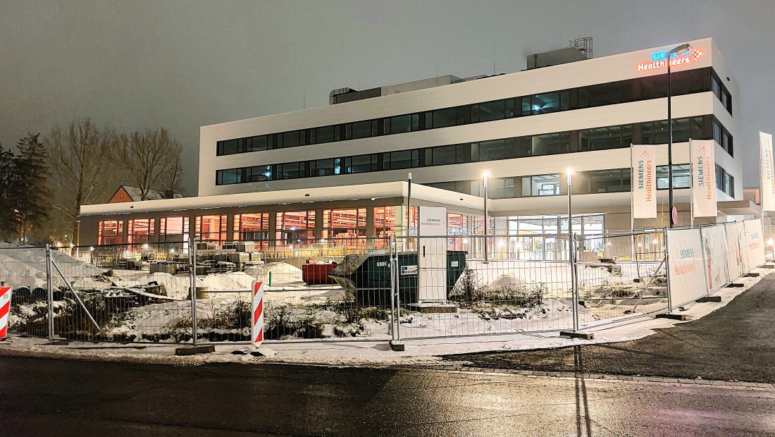 Foto: Martin Zehrer - Die Siemens Healthineers Niederlassung in Kemnath ist bei Nacht gut sichtbar, mit einem Neubau, der in hellen Farben beleuchtet wird. <br />
Die Umgebung zeigt eine Baustelle, 