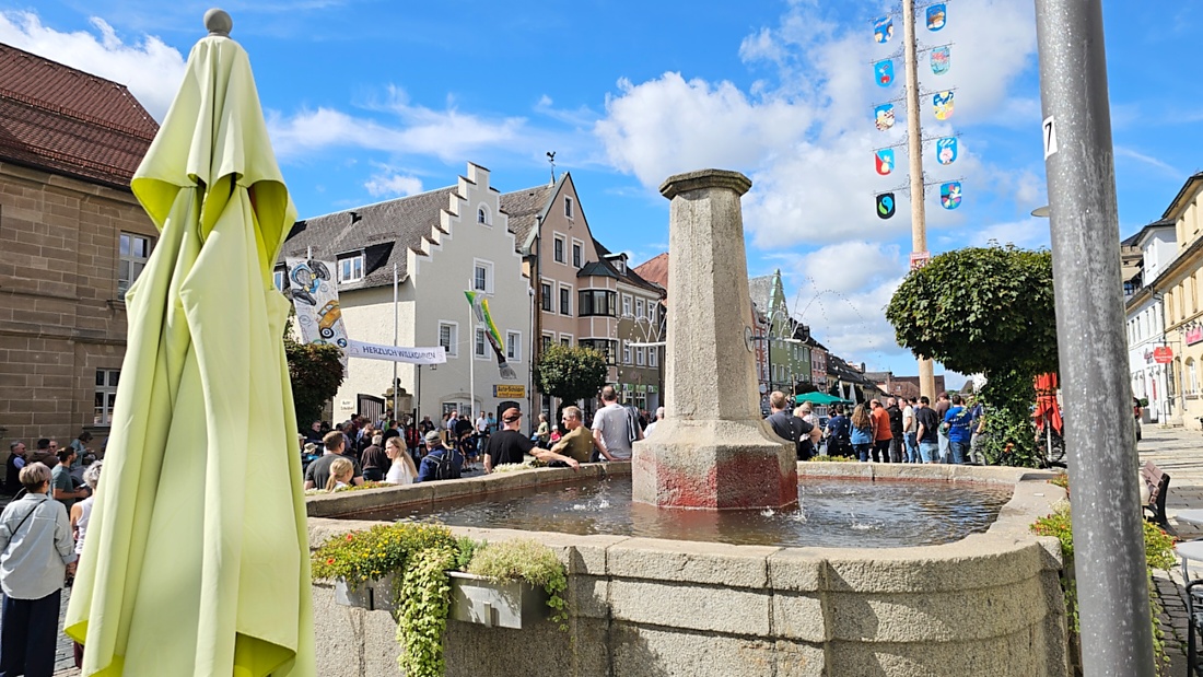 Jede Menge automobile Schätze auf dem Kemnather Stadtplatz

Ein echtes Paradies für Oldtimerfreunde gab es am Samstag beim großen Oldtimertreffen in Kemnath zu erleben. Ab 10 Uhr gehörte der wunderschöne historische Stadtplatz den automobilen Schätzen vergangener Jahrzehnte. Bei bestem Oldtimerwetter präsentierten sich die liebevoll gepflegten Fahrzeuge vor einer traumhaften Kulisse – und natürlich ließen sich das auch jede Menge Zuschauer nicht entgehen.

Dicht an dicht standen die Besucher entlang des Stadtplatzes, als ein Klassiker nach dem anderen zur Fahrzeugvorstellung vorfuhr. Dabei gab es nicht nur jede Menge Chrom, glänzenden Lack und den unverwechselbaren Klang alter Motoren zu bestaunen, sondern auch viel Wissenswertes zu hören.

Wie jedes Jahr hatte Elmar Högl das Mikrofon fest im Griff. Souverän und mit enormem Fachwissen stellte er die einzelnen Fahrzeuge vor, erzählte von Baujahren, Motorisierung und technischen Besonderheiten und hatte dabei immer wieder interessante Details zu den Oldtimern parat.

Und eigentlich ist Elmar Högl aus dem Kemnather Oldtimertreffen kaum wegzudenken. Er ist nicht nur die bekannte Stimme am Mikrofon, sondern zugleich Hauptorganisator und so etwas wie das „Herz“ des Treffens. Gemeinsam mit dem KEM-Verband und der Stadt Kemnath sorgt er dafür, dass die Freunde historischer Fahrzeuge Jahr für Jahr in Kemnath zusammenkommen.

Zur Fahrzeugvorstellung gehörte natürlich auch die Übergabe der Urkunden. Diese Aufgabe übernahm Hermann Schraml, unterstützt von Stefan Wöhrl.

Und besser hätte es an diesem Vormittag eigentlich kaum passen können: herrliches Wetter, ein voller Stadtplatz, viele begeisterte Zuschauer und mittendrin jede Menge automobile Zeitgeschichte auf zwei und vier Rädern.

Nach der Vorstellung blieb noch genügend Zeit, die Oldtimer aus nächster Nähe zu betrachten, mit den Besitzern ins Gespräch zu kommen und natürlich jede Menge Fotos zu machen.

Am Nachmittag wartete dann bereits der nächste Höhepunkt auf die Teilnehmer. Um 13:15 Uhr machten sich die historischen Fahrzeuge zur gemeinsamen Ausfahrt auf den Weg. Über Berndorf, Haidenaab und Weidenberg führte die Tour unter anderem nach Goldkronach, wo eine längere Rast eingelegt wurde, bevor es schließlich wieder zurück nach Kemnath ging.

Und jetzt viel Spaß beim Durchklicken durch unsere Bilder vom Kemnather Oldtimertreffen 2026!