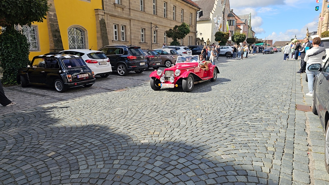 Jede Menge automobile Schätze auf dem Kemnather Stadtplatz

Ein echtes Paradies für Oldtimerfreunde gab es am Samstag beim großen Oldtimertreffen in Kemnath zu erleben. Ab 10 Uhr gehörte der wunderschöne historische Stadtplatz den automobilen Schätzen vergangener Jahrzehnte. Bei bestem Oldtimerwetter präsentierten sich die liebevoll gepflegten Fahrzeuge vor einer traumhaften Kulisse – und natürlich ließen sich das auch jede Menge Zuschauer nicht entgehen.

Dicht an dicht standen die Besucher entlang des Stadtplatzes, als ein Klassiker nach dem anderen zur Fahrzeugvorstellung vorfuhr. Dabei gab es nicht nur jede Menge Chrom, glänzenden Lack und den unverwechselbaren Klang alter Motoren zu bestaunen, sondern auch viel Wissenswertes zu hören.

Wie jedes Jahr hatte Elmar Högl das Mikrofon fest im Griff. Souverän und mit enormem Fachwissen stellte er die einzelnen Fahrzeuge vor, erzählte von Baujahren, Motorisierung und technischen Besonderheiten und hatte dabei immer wieder interessante Details zu den Oldtimern parat.

Und eigentlich ist Elmar Högl aus dem Kemnather Oldtimertreffen kaum wegzudenken. Er ist nicht nur die bekannte Stimme am Mikrofon, sondern zugleich Hauptorganisator und so etwas wie das „Herz“ des Treffens. Gemeinsam mit dem KEM-Verband und der Stadt Kemnath sorgt er dafür, dass die Freunde historischer Fahrzeuge Jahr für Jahr in Kemnath zusammenkommen.

Zur Fahrzeugvorstellung gehörte natürlich auch die Übergabe der Urkunden. Diese Aufgabe übernahm Hermann Schraml, unterstützt von Stefan Wöhrl.

Und besser hätte es an diesem Vormittag eigentlich kaum passen können: herrliches Wetter, ein voller Stadtplatz, viele begeisterte Zuschauer und mittendrin jede Menge automobile Zeitgeschichte auf zwei und vier Rädern.

Nach der Vorstellung blieb noch genügend Zeit, die Oldtimer aus nächster Nähe zu betrachten, mit den Besitzern ins Gespräch zu kommen und natürlich jede Menge Fotos zu machen.

Am Nachmittag wartete dann bereits der nächste Höhepunkt auf die Teilnehmer. Um 13:15 Uhr machten sich die historischen Fahrzeuge zur gemeinsamen Ausfahrt auf den Weg. Über Berndorf, Haidenaab und Weidenberg führte die Tour unter anderem nach Goldkronach, wo eine längere Rast eingelegt wurde, bevor es schließlich wieder zurück nach Kemnath ging.

Und jetzt viel Spaß beim Durchklicken durch unsere Bilder vom Kemnather Oldtimertreffen 2026!