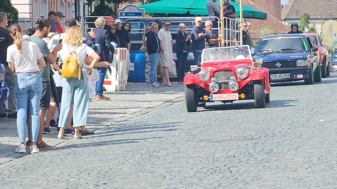 Jede Menge automobile Schätze auf dem Kemnather Stadtplatz

Ein echtes Paradies für Oldtimerfreunde gab es am Samstag beim großen Oldtimertreffen in Kemnath zu erleben. Ab 10 Uhr gehörte der wunderschöne historische Stadtplatz den automobilen Schätzen vergangener Jahrzehnte. Bei bestem Oldtimerwetter präsentierten sich die liebevoll gepflegten Fahrzeuge vor einer traumhaften Kulisse – und natürlich ließen sich das auch jede Menge Zuschauer nicht entgehen.

Dicht an dicht standen die Besucher entlang des Stadtplatzes, als ein Klassiker nach dem anderen zur Fahrzeugvorstellung vorfuhr. Dabei gab es nicht nur jede Menge Chrom, glänzenden Lack und den unverwechselbaren Klang alter Motoren zu bestaunen, sondern auch viel Wissenswertes zu hören.

Wie jedes Jahr hatte Elmar Högl das Mikrofon fest im Griff. Souverän und mit enormem Fachwissen stellte er die einzelnen Fahrzeuge vor, erzählte von Baujahren, Motorisierung und technischen Besonderheiten und hatte dabei immer wieder interessante Details zu den Oldtimern parat.

Und eigentlich ist Elmar Högl aus dem Kemnather Oldtimertreffen kaum wegzudenken. Er ist nicht nur die bekannte Stimme am Mikrofon, sondern zugleich Hauptorganisator und so etwas wie das „Herz“ des Treffens. Gemeinsam mit dem KEM-Verband und der Stadt Kemnath sorgt er dafür, dass die Freunde historischer Fahrzeuge Jahr für Jahr in Kemnath zusammenkommen.

Zur Fahrzeugvorstellung gehörte natürlich auch die Übergabe der Urkunden. Diese Aufgabe übernahm Hermann Schraml, unterstützt von Stefan Wöhrl.

Und besser hätte es an diesem Vormittag eigentlich kaum passen können: herrliches Wetter, ein voller Stadtplatz, viele begeisterte Zuschauer und mittendrin jede Menge automobile Zeitgeschichte auf zwei und vier Rädern.

Nach der Vorstellung blieb noch genügend Zeit, die Oldtimer aus nächster Nähe zu betrachten, mit den Besitzern ins Gespräch zu kommen und natürlich jede Menge Fotos zu machen.

Am Nachmittag wartete dann bereits der nächste Höhepunkt auf die Teilnehmer. Um 13:15 Uhr machten sich die historischen Fahrzeuge zur gemeinsamen Ausfahrt auf den Weg. Über Berndorf, Haidenaab und Weidenberg führte die Tour unter anderem nach Goldkronach, wo eine längere Rast eingelegt wurde, bevor es schließlich wieder zurück nach Kemnath ging.

Und jetzt viel Spaß beim Durchklicken durch unsere Bilder vom Kemnather Oldtimertreffen 2026!