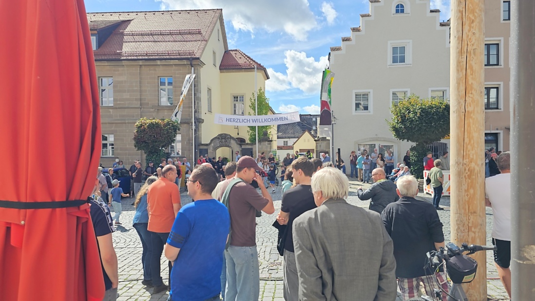 Jede Menge automobile Schätze auf dem Kemnather Stadtplatz

Ein echtes Paradies für Oldtimerfreunde gab es am Samstag beim großen Oldtimertreffen in Kemnath zu erleben. Ab 10 Uhr gehörte der wunderschöne historische Stadtplatz den automobilen Schätzen vergangener Jahrzehnte. Bei bestem Oldtimerwetter präsentierten sich die liebevoll gepflegten Fahrzeuge vor einer traumhaften Kulisse – und natürlich ließen sich das auch jede Menge Zuschauer nicht entgehen.

Dicht an dicht standen die Besucher entlang des Stadtplatzes, als ein Klassiker nach dem anderen zur Fahrzeugvorstellung vorfuhr. Dabei gab es nicht nur jede Menge Chrom, glänzenden Lack und den unverwechselbaren Klang alter Motoren zu bestaunen, sondern auch viel Wissenswertes zu hören.

Wie jedes Jahr hatte Elmar Högl das Mikrofon fest im Griff. Souverän und mit enormem Fachwissen stellte er die einzelnen Fahrzeuge vor, erzählte von Baujahren, Motorisierung und technischen Besonderheiten und hatte dabei immer wieder interessante Details zu den Oldtimern parat.

Und eigentlich ist Elmar Högl aus dem Kemnather Oldtimertreffen kaum wegzudenken. Er ist nicht nur die bekannte Stimme am Mikrofon, sondern zugleich Hauptorganisator und so etwas wie das „Herz“ des Treffens. Gemeinsam mit dem KEM-Verband und der Stadt Kemnath sorgt er dafür, dass die Freunde historischer Fahrzeuge Jahr für Jahr in Kemnath zusammenkommen.

Zur Fahrzeugvorstellung gehörte natürlich auch die Übergabe der Urkunden. Diese Aufgabe übernahm Hermann Schraml, unterstützt von Stefan Wöhrl.

Und besser hätte es an diesem Vormittag eigentlich kaum passen können: herrliches Wetter, ein voller Stadtplatz, viele begeisterte Zuschauer und mittendrin jede Menge automobile Zeitgeschichte auf zwei und vier Rädern.

Nach der Vorstellung blieb noch genügend Zeit, die Oldtimer aus nächster Nähe zu betrachten, mit den Besitzern ins Gespräch zu kommen und natürlich jede Menge Fotos zu machen.

Am Nachmittag wartete dann bereits der nächste Höhepunkt auf die Teilnehmer. Um 13:15 Uhr machten sich die historischen Fahrzeuge zur gemeinsamen Ausfahrt auf den Weg. Über Berndorf, Haidenaab und Weidenberg führte die Tour unter anderem nach Goldkronach, wo eine längere Rast eingelegt wurde, bevor es schließlich wieder zurück nach Kemnath ging.

Und jetzt viel Spaß beim Durchklicken durch unsere Bilder vom Kemnather Oldtimertreffen 2026!