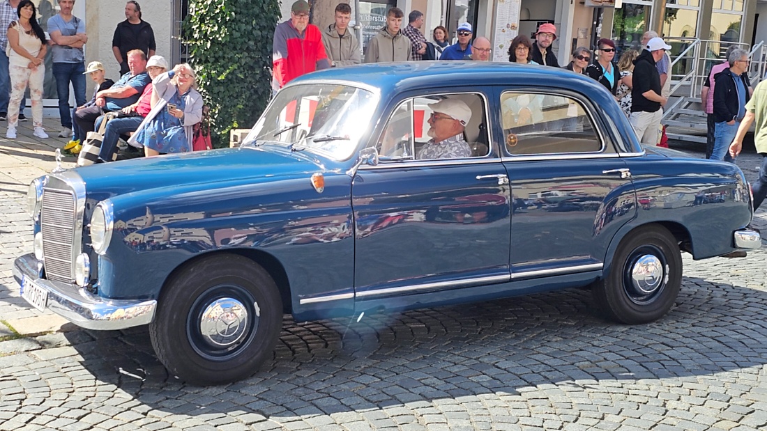 Jede Menge automobile Schätze auf dem Kemnather Stadtplatz

Ein echtes Paradies für Oldtimerfreunde gab es am Samstag beim großen Oldtimertreffen in Kemnath zu erleben. Ab 10 Uhr gehörte der wunderschöne historische Stadtplatz den automobilen Schätzen vergangener Jahrzehnte. Bei bestem Oldtimerwetter präsentierten sich die liebevoll gepflegten Fahrzeuge vor einer traumhaften Kulisse – und natürlich ließen sich das auch jede Menge Zuschauer nicht entgehen.

Dicht an dicht standen die Besucher entlang des Stadtplatzes, als ein Klassiker nach dem anderen zur Fahrzeugvorstellung vorfuhr. Dabei gab es nicht nur jede Menge Chrom, glänzenden Lack und den unverwechselbaren Klang alter Motoren zu bestaunen, sondern auch viel Wissenswertes zu hören.

Wie jedes Jahr hatte Elmar Högl das Mikrofon fest im Griff. Souverän und mit enormem Fachwissen stellte er die einzelnen Fahrzeuge vor, erzählte von Baujahren, Motorisierung und technischen Besonderheiten und hatte dabei immer wieder interessante Details zu den Oldtimern parat.

Und eigentlich ist Elmar Högl aus dem Kemnather Oldtimertreffen kaum wegzudenken. Er ist nicht nur die bekannte Stimme am Mikrofon, sondern zugleich Hauptorganisator und so etwas wie das „Herz“ des Treffens. Gemeinsam mit dem KEM-Verband und der Stadt Kemnath sorgt er dafür, dass die Freunde historischer Fahrzeuge Jahr für Jahr in Kemnath zusammenkommen.

Zur Fahrzeugvorstellung gehörte natürlich auch die Übergabe der Urkunden. Diese Aufgabe übernahm Hermann Schraml, unterstützt von Stefan Wöhrl.

Und besser hätte es an diesem Vormittag eigentlich kaum passen können: herrliches Wetter, ein voller Stadtplatz, viele begeisterte Zuschauer und mittendrin jede Menge automobile Zeitgeschichte auf zwei und vier Rädern.

Nach der Vorstellung blieb noch genügend Zeit, die Oldtimer aus nächster Nähe zu betrachten, mit den Besitzern ins Gespräch zu kommen und natürlich jede Menge Fotos zu machen.

Am Nachmittag wartete dann bereits der nächste Höhepunkt auf die Teilnehmer. Um 13:15 Uhr machten sich die historischen Fahrzeuge zur gemeinsamen Ausfahrt auf den Weg. Über Berndorf, Haidenaab und Weidenberg führte die Tour unter anderem nach Goldkronach, wo eine längere Rast eingelegt wurde, bevor es schließlich wieder zurück nach Kemnath ging.

Und jetzt viel Spaß beim Durchklicken durch unsere Bilder vom Kemnather Oldtimertreffen 2026!