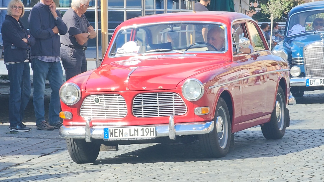 Jede Menge automobile Schätze auf dem Kemnather Stadtplatz

Ein echtes Paradies für Oldtimerfreunde gab es am Samstag beim großen Oldtimertreffen in Kemnath zu erleben. Ab 10 Uhr gehörte der wunderschöne historische Stadtplatz den automobilen Schätzen vergangener Jahrzehnte. Bei bestem Oldtimerwetter präsentierten sich die liebevoll gepflegten Fahrzeuge vor einer traumhaften Kulisse – und natürlich ließen sich das auch jede Menge Zuschauer nicht entgehen.

Dicht an dicht standen die Besucher entlang des Stadtplatzes, als ein Klassiker nach dem anderen zur Fahrzeugvorstellung vorfuhr. Dabei gab es nicht nur jede Menge Chrom, glänzenden Lack und den unverwechselbaren Klang alter Motoren zu bestaunen, sondern auch viel Wissenswertes zu hören.

Wie jedes Jahr hatte Elmar Högl das Mikrofon fest im Griff. Souverän und mit enormem Fachwissen stellte er die einzelnen Fahrzeuge vor, erzählte von Baujahren, Motorisierung und technischen Besonderheiten und hatte dabei immer wieder interessante Details zu den Oldtimern parat.

Und eigentlich ist Elmar Högl aus dem Kemnather Oldtimertreffen kaum wegzudenken. Er ist nicht nur die bekannte Stimme am Mikrofon, sondern zugleich Hauptorganisator und so etwas wie das „Herz“ des Treffens. Gemeinsam mit dem KEM-Verband und der Stadt Kemnath sorgt er dafür, dass die Freunde historischer Fahrzeuge Jahr für Jahr in Kemnath zusammenkommen.

Zur Fahrzeugvorstellung gehörte natürlich auch die Übergabe der Urkunden. Diese Aufgabe übernahm Hermann Schraml, unterstützt von Stefan Wöhrl.

Und besser hätte es an diesem Vormittag eigentlich kaum passen können: herrliches Wetter, ein voller Stadtplatz, viele begeisterte Zuschauer und mittendrin jede Menge automobile Zeitgeschichte auf zwei und vier Rädern.

Nach der Vorstellung blieb noch genügend Zeit, die Oldtimer aus nächster Nähe zu betrachten, mit den Besitzern ins Gespräch zu kommen und natürlich jede Menge Fotos zu machen.

Am Nachmittag wartete dann bereits der nächste Höhepunkt auf die Teilnehmer. Um 13:15 Uhr machten sich die historischen Fahrzeuge zur gemeinsamen Ausfahrt auf den Weg. Über Berndorf, Haidenaab und Weidenberg führte die Tour unter anderem nach Goldkronach, wo eine längere Rast eingelegt wurde, bevor es schließlich wieder zurück nach Kemnath ging.

Und jetzt viel Spaß beim Durchklicken durch unsere Bilder vom Kemnather Oldtimertreffen 2026!