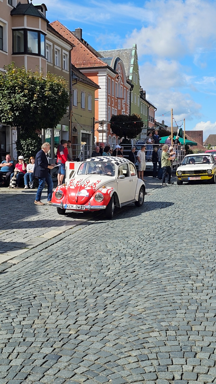 Jede Menge automobile Schätze auf dem Kemnather Stadtplatz

Ein echtes Paradies für Oldtimerfreunde gab es am Samstag beim großen Oldtimertreffen in Kemnath zu erleben. Ab 10 Uhr gehörte der wunderschöne historische Stadtplatz den automobilen Schätzen vergangener Jahrzehnte. Bei bestem Oldtimerwetter präsentierten sich die liebevoll gepflegten Fahrzeuge vor einer traumhaften Kulisse – und natürlich ließen sich das auch jede Menge Zuschauer nicht entgehen.

Dicht an dicht standen die Besucher entlang des Stadtplatzes, als ein Klassiker nach dem anderen zur Fahrzeugvorstellung vorfuhr. Dabei gab es nicht nur jede Menge Chrom, glänzenden Lack und den unverwechselbaren Klang alter Motoren zu bestaunen, sondern auch viel Wissenswertes zu hören.

Wie jedes Jahr hatte Elmar Högl das Mikrofon fest im Griff. Souverän und mit enormem Fachwissen stellte er die einzelnen Fahrzeuge vor, erzählte von Baujahren, Motorisierung und technischen Besonderheiten und hatte dabei immer wieder interessante Details zu den Oldtimern parat.

Und eigentlich ist Elmar Högl aus dem Kemnather Oldtimertreffen kaum wegzudenken. Er ist nicht nur die bekannte Stimme am Mikrofon, sondern zugleich Hauptorganisator und so etwas wie das „Herz“ des Treffens. Gemeinsam mit dem KEM-Verband und der Stadt Kemnath sorgt er dafür, dass die Freunde historischer Fahrzeuge Jahr für Jahr in Kemnath zusammenkommen.

Zur Fahrzeugvorstellung gehörte natürlich auch die Übergabe der Urkunden. Diese Aufgabe übernahm Hermann Schraml, unterstützt von Stefan Wöhrl.

Und besser hätte es an diesem Vormittag eigentlich kaum passen können: herrliches Wetter, ein voller Stadtplatz, viele begeisterte Zuschauer und mittendrin jede Menge automobile Zeitgeschichte auf zwei und vier Rädern.

Nach der Vorstellung blieb noch genügend Zeit, die Oldtimer aus nächster Nähe zu betrachten, mit den Besitzern ins Gespräch zu kommen und natürlich jede Menge Fotos zu machen.

Am Nachmittag wartete dann bereits der nächste Höhepunkt auf die Teilnehmer. Um 13:15 Uhr machten sich die historischen Fahrzeuge zur gemeinsamen Ausfahrt auf den Weg. Über Berndorf, Haidenaab und Weidenberg führte die Tour unter anderem nach Goldkronach, wo eine längere Rast eingelegt wurde, bevor es schließlich wieder zurück nach Kemnath ging.

Und jetzt viel Spaß beim Durchklicken durch unsere Bilder vom Kemnather Oldtimertreffen 2026!