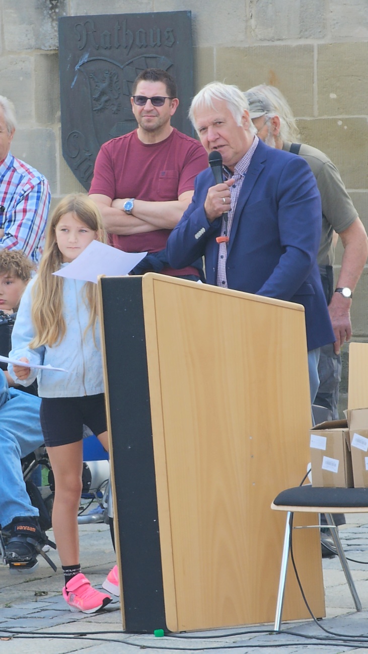 Jede Menge automobile Schätze auf dem Kemnather Stadtplatz

Ein echtes Paradies für Oldtimerfreunde gab es am Samstag beim großen Oldtimertreffen in Kemnath zu erleben. Ab 10 Uhr gehörte der wunderschöne historische Stadtplatz den automobilen Schätzen vergangener Jahrzehnte. Bei bestem Oldtimerwetter präsentierten sich die liebevoll gepflegten Fahrzeuge vor einer traumhaften Kulisse – und natürlich ließen sich das auch jede Menge Zuschauer nicht entgehen.

Dicht an dicht standen die Besucher entlang des Stadtplatzes, als ein Klassiker nach dem anderen zur Fahrzeugvorstellung vorfuhr. Dabei gab es nicht nur jede Menge Chrom, glänzenden Lack und den unverwechselbaren Klang alter Motoren zu bestaunen, sondern auch viel Wissenswertes zu hören.

Wie jedes Jahr hatte Elmar Högl das Mikrofon fest im Griff. Souverän und mit enormem Fachwissen stellte er die einzelnen Fahrzeuge vor, erzählte von Baujahren, Motorisierung und technischen Besonderheiten und hatte dabei immer wieder interessante Details zu den Oldtimern parat.

Und eigentlich ist Elmar Högl aus dem Kemnather Oldtimertreffen kaum wegzudenken. Er ist nicht nur die bekannte Stimme am Mikrofon, sondern zugleich Hauptorganisator und so etwas wie das „Herz“ des Treffens. Gemeinsam mit dem KEM-Verband und der Stadt Kemnath sorgt er dafür, dass die Freunde historischer Fahrzeuge Jahr für Jahr in Kemnath zusammenkommen.

Zur Fahrzeugvorstellung gehörte natürlich auch die Übergabe der Urkunden. Diese Aufgabe übernahm Hermann Schraml, unterstützt von Stefan Wöhrl.

Und besser hätte es an diesem Vormittag eigentlich kaum passen können: herrliches Wetter, ein voller Stadtplatz, viele begeisterte Zuschauer und mittendrin jede Menge automobile Zeitgeschichte auf zwei und vier Rädern.

Nach der Vorstellung blieb noch genügend Zeit, die Oldtimer aus nächster Nähe zu betrachten, mit den Besitzern ins Gespräch zu kommen und natürlich jede Menge Fotos zu machen.

Am Nachmittag wartete dann bereits der nächste Höhepunkt auf die Teilnehmer. Um 13:15 Uhr machten sich die historischen Fahrzeuge zur gemeinsamen Ausfahrt auf den Weg. Über Berndorf, Haidenaab und Weidenberg führte die Tour unter anderem nach Goldkronach, wo eine längere Rast eingelegt wurde, bevor es schließlich wieder zurück nach Kemnath ging.

Und jetzt viel Spaß beim Durchklicken durch unsere Bilder vom Kemnather Oldtimertreffen 2026!
