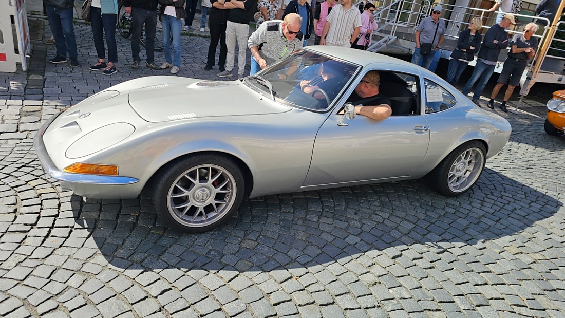 Jede Menge automobile Schätze auf dem Kemnather Stadtplatz

Ein echtes Paradies für Oldtimerfreunde gab es am Samstag beim großen Oldtimertreffen in Kemnath zu erleben. Ab 10 Uhr gehörte der wunderschöne historische Stadtplatz den automobilen Schätzen vergangener Jahrzehnte. Bei bestem Oldtimerwetter präsentierten sich die liebevoll gepflegten Fahrzeuge vor einer traumhaften Kulisse – und natürlich ließen sich das auch jede Menge Zuschauer nicht entgehen.

Dicht an dicht standen die Besucher entlang des Stadtplatzes, als ein Klassiker nach dem anderen zur Fahrzeugvorstellung vorfuhr. Dabei gab es nicht nur jede Menge Chrom, glänzenden Lack und den unverwechselbaren Klang alter Motoren zu bestaunen, sondern auch viel Wissenswertes zu hören.

Wie jedes Jahr hatte Elmar Högl das Mikrofon fest im Griff. Souverän und mit enormem Fachwissen stellte er die einzelnen Fahrzeuge vor, erzählte von Baujahren, Motorisierung und technischen Besonderheiten und hatte dabei immer wieder interessante Details zu den Oldtimern parat.

Und eigentlich ist Elmar Högl aus dem Kemnather Oldtimertreffen kaum wegzudenken. Er ist nicht nur die bekannte Stimme am Mikrofon, sondern zugleich Hauptorganisator und so etwas wie das „Herz“ des Treffens. Gemeinsam mit dem KEM-Verband und der Stadt Kemnath sorgt er dafür, dass die Freunde historischer Fahrzeuge Jahr für Jahr in Kemnath zusammenkommen.

Zur Fahrzeugvorstellung gehörte natürlich auch die Übergabe der Urkunden. Diese Aufgabe übernahm Hermann Schraml, unterstützt von Stefan Wöhrl.

Und besser hätte es an diesem Vormittag eigentlich kaum passen können: herrliches Wetter, ein voller Stadtplatz, viele begeisterte Zuschauer und mittendrin jede Menge automobile Zeitgeschichte auf zwei und vier Rädern.

Nach der Vorstellung blieb noch genügend Zeit, die Oldtimer aus nächster Nähe zu betrachten, mit den Besitzern ins Gespräch zu kommen und natürlich jede Menge Fotos zu machen.

Am Nachmittag wartete dann bereits der nächste Höhepunkt auf die Teilnehmer. Um 13:15 Uhr machten sich die historischen Fahrzeuge zur gemeinsamen Ausfahrt auf den Weg. Über Berndorf, Haidenaab und Weidenberg führte die Tour unter anderem nach Goldkronach, wo eine längere Rast eingelegt wurde, bevor es schließlich wieder zurück nach Kemnath ging.

Und jetzt viel Spaß beim Durchklicken durch unsere Bilder vom Kemnather Oldtimertreffen 2026!