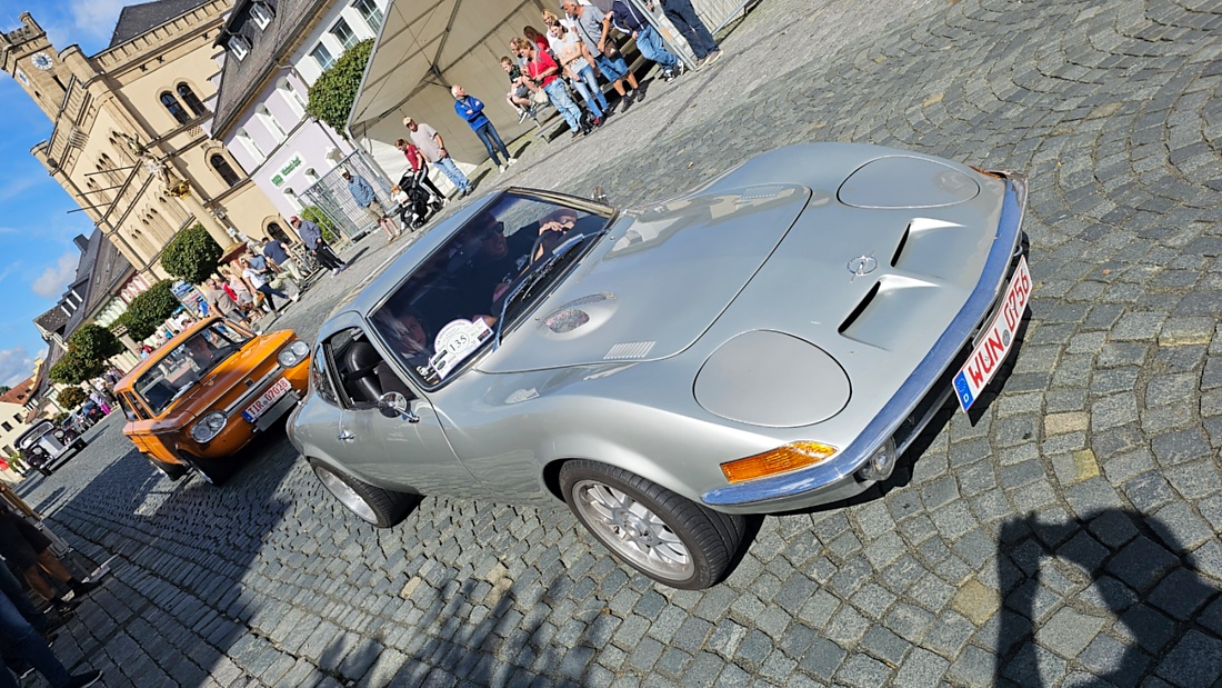Jede Menge automobile Schätze auf dem Kemnather Stadtplatz

Ein echtes Paradies für Oldtimerfreunde gab es am Samstag beim großen Oldtimertreffen in Kemnath zu erleben. Ab 10 Uhr gehörte der wunderschöne historische Stadtplatz den automobilen Schätzen vergangener Jahrzehnte. Bei bestem Oldtimerwetter präsentierten sich die liebevoll gepflegten Fahrzeuge vor einer traumhaften Kulisse – und natürlich ließen sich das auch jede Menge Zuschauer nicht entgehen.

Dicht an dicht standen die Besucher entlang des Stadtplatzes, als ein Klassiker nach dem anderen zur Fahrzeugvorstellung vorfuhr. Dabei gab es nicht nur jede Menge Chrom, glänzenden Lack und den unverwechselbaren Klang alter Motoren zu bestaunen, sondern auch viel Wissenswertes zu hören.

Wie jedes Jahr hatte Elmar Högl das Mikrofon fest im Griff. Souverän und mit enormem Fachwissen stellte er die einzelnen Fahrzeuge vor, erzählte von Baujahren, Motorisierung und technischen Besonderheiten und hatte dabei immer wieder interessante Details zu den Oldtimern parat.

Und eigentlich ist Elmar Högl aus dem Kemnather Oldtimertreffen kaum wegzudenken. Er ist nicht nur die bekannte Stimme am Mikrofon, sondern zugleich Hauptorganisator und so etwas wie das „Herz“ des Treffens. Gemeinsam mit dem KEM-Verband und der Stadt Kemnath sorgt er dafür, dass die Freunde historischer Fahrzeuge Jahr für Jahr in Kemnath zusammenkommen.

Zur Fahrzeugvorstellung gehörte natürlich auch die Übergabe der Urkunden. Diese Aufgabe übernahm Hermann Schraml, unterstützt von Stefan Wöhrl.

Und besser hätte es an diesem Vormittag eigentlich kaum passen können: herrliches Wetter, ein voller Stadtplatz, viele begeisterte Zuschauer und mittendrin jede Menge automobile Zeitgeschichte auf zwei und vier Rädern.

Nach der Vorstellung blieb noch genügend Zeit, die Oldtimer aus nächster Nähe zu betrachten, mit den Besitzern ins Gespräch zu kommen und natürlich jede Menge Fotos zu machen.

Am Nachmittag wartete dann bereits der nächste Höhepunkt auf die Teilnehmer. Um 13:15 Uhr machten sich die historischen Fahrzeuge zur gemeinsamen Ausfahrt auf den Weg. Über Berndorf, Haidenaab und Weidenberg führte die Tour unter anderem nach Goldkronach, wo eine längere Rast eingelegt wurde, bevor es schließlich wieder zurück nach Kemnath ging.

Und jetzt viel Spaß beim Durchklicken durch unsere Bilder vom Kemnather Oldtimertreffen 2026!