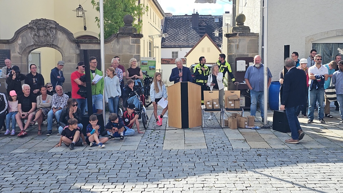 Jede Menge automobile Schätze auf dem Kemnather Stadtplatz

Ein echtes Paradies für Oldtimerfreunde gab es am Samstag beim großen Oldtimertreffen in Kemnath zu erleben. Ab 10 Uhr gehörte der wunderschöne historische Stadtplatz den automobilen Schätzen vergangener Jahrzehnte. Bei bestem Oldtimerwetter präsentierten sich die liebevoll gepflegten Fahrzeuge vor einer traumhaften Kulisse – und natürlich ließen sich das auch jede Menge Zuschauer nicht entgehen.

Dicht an dicht standen die Besucher entlang des Stadtplatzes, als ein Klassiker nach dem anderen zur Fahrzeugvorstellung vorfuhr. Dabei gab es nicht nur jede Menge Chrom, glänzenden Lack und den unverwechselbaren Klang alter Motoren zu bestaunen, sondern auch viel Wissenswertes zu hören.

Wie jedes Jahr hatte Elmar Högl das Mikrofon fest im Griff. Souverän und mit enormem Fachwissen stellte er die einzelnen Fahrzeuge vor, erzählte von Baujahren, Motorisierung und technischen Besonderheiten und hatte dabei immer wieder interessante Details zu den Oldtimern parat.

Und eigentlich ist Elmar Högl aus dem Kemnather Oldtimertreffen kaum wegzudenken. Er ist nicht nur die bekannte Stimme am Mikrofon, sondern zugleich Hauptorganisator und so etwas wie das „Herz“ des Treffens. Gemeinsam mit dem KEM-Verband und der Stadt Kemnath sorgt er dafür, dass die Freunde historischer Fahrzeuge Jahr für Jahr in Kemnath zusammenkommen.

Zur Fahrzeugvorstellung gehörte natürlich auch die Übergabe der Urkunden. Diese Aufgabe übernahm Hermann Schraml, unterstützt von Stefan Wöhrl.

Und besser hätte es an diesem Vormittag eigentlich kaum passen können: herrliches Wetter, ein voller Stadtplatz, viele begeisterte Zuschauer und mittendrin jede Menge automobile Zeitgeschichte auf zwei und vier Rädern.

Nach der Vorstellung blieb noch genügend Zeit, die Oldtimer aus nächster Nähe zu betrachten, mit den Besitzern ins Gespräch zu kommen und natürlich jede Menge Fotos zu machen.

Am Nachmittag wartete dann bereits der nächste Höhepunkt auf die Teilnehmer. Um 13:15 Uhr machten sich die historischen Fahrzeuge zur gemeinsamen Ausfahrt auf den Weg. Über Berndorf, Haidenaab und Weidenberg führte die Tour unter anderem nach Goldkronach, wo eine längere Rast eingelegt wurde, bevor es schließlich wieder zurück nach Kemnath ging.

Und jetzt viel Spaß beim Durchklicken durch unsere Bilder vom Kemnather Oldtimertreffen 2026!