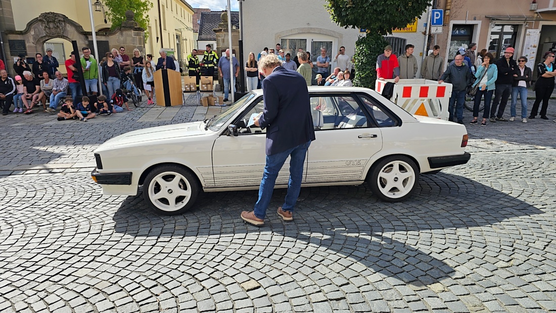 Jede Menge automobile Schätze auf dem Kemnather Stadtplatz

Ein echtes Paradies für Oldtimerfreunde gab es am Samstag beim großen Oldtimertreffen in Kemnath zu erleben. Ab 10 Uhr gehörte der wunderschöne historische Stadtplatz den automobilen Schätzen vergangener Jahrzehnte. Bei bestem Oldtimerwetter präsentierten sich die liebevoll gepflegten Fahrzeuge vor einer traumhaften Kulisse – und natürlich ließen sich das auch jede Menge Zuschauer nicht entgehen.

Dicht an dicht standen die Besucher entlang des Stadtplatzes, als ein Klassiker nach dem anderen zur Fahrzeugvorstellung vorfuhr. Dabei gab es nicht nur jede Menge Chrom, glänzenden Lack und den unverwechselbaren Klang alter Motoren zu bestaunen, sondern auch viel Wissenswertes zu hören.

Wie jedes Jahr hatte Elmar Högl das Mikrofon fest im Griff. Souverän und mit enormem Fachwissen stellte er die einzelnen Fahrzeuge vor, erzählte von Baujahren, Motorisierung und technischen Besonderheiten und hatte dabei immer wieder interessante Details zu den Oldtimern parat.

Und eigentlich ist Elmar Högl aus dem Kemnather Oldtimertreffen kaum wegzudenken. Er ist nicht nur die bekannte Stimme am Mikrofon, sondern zugleich Hauptorganisator und so etwas wie das „Herz“ des Treffens. Gemeinsam mit dem KEM-Verband und der Stadt Kemnath sorgt er dafür, dass die Freunde historischer Fahrzeuge Jahr für Jahr in Kemnath zusammenkommen.

Zur Fahrzeugvorstellung gehörte natürlich auch die Übergabe der Urkunden. Diese Aufgabe übernahm Hermann Schraml, unterstützt von Stefan Wöhrl.

Und besser hätte es an diesem Vormittag eigentlich kaum passen können: herrliches Wetter, ein voller Stadtplatz, viele begeisterte Zuschauer und mittendrin jede Menge automobile Zeitgeschichte auf zwei und vier Rädern.

Nach der Vorstellung blieb noch genügend Zeit, die Oldtimer aus nächster Nähe zu betrachten, mit den Besitzern ins Gespräch zu kommen und natürlich jede Menge Fotos zu machen.

Am Nachmittag wartete dann bereits der nächste Höhepunkt auf die Teilnehmer. Um 13:15 Uhr machten sich die historischen Fahrzeuge zur gemeinsamen Ausfahrt auf den Weg. Über Berndorf, Haidenaab und Weidenberg führte die Tour unter anderem nach Goldkronach, wo eine längere Rast eingelegt wurde, bevor es schließlich wieder zurück nach Kemnath ging.

Und jetzt viel Spaß beim Durchklicken durch unsere Bilder vom Kemnather Oldtimertreffen 2026!