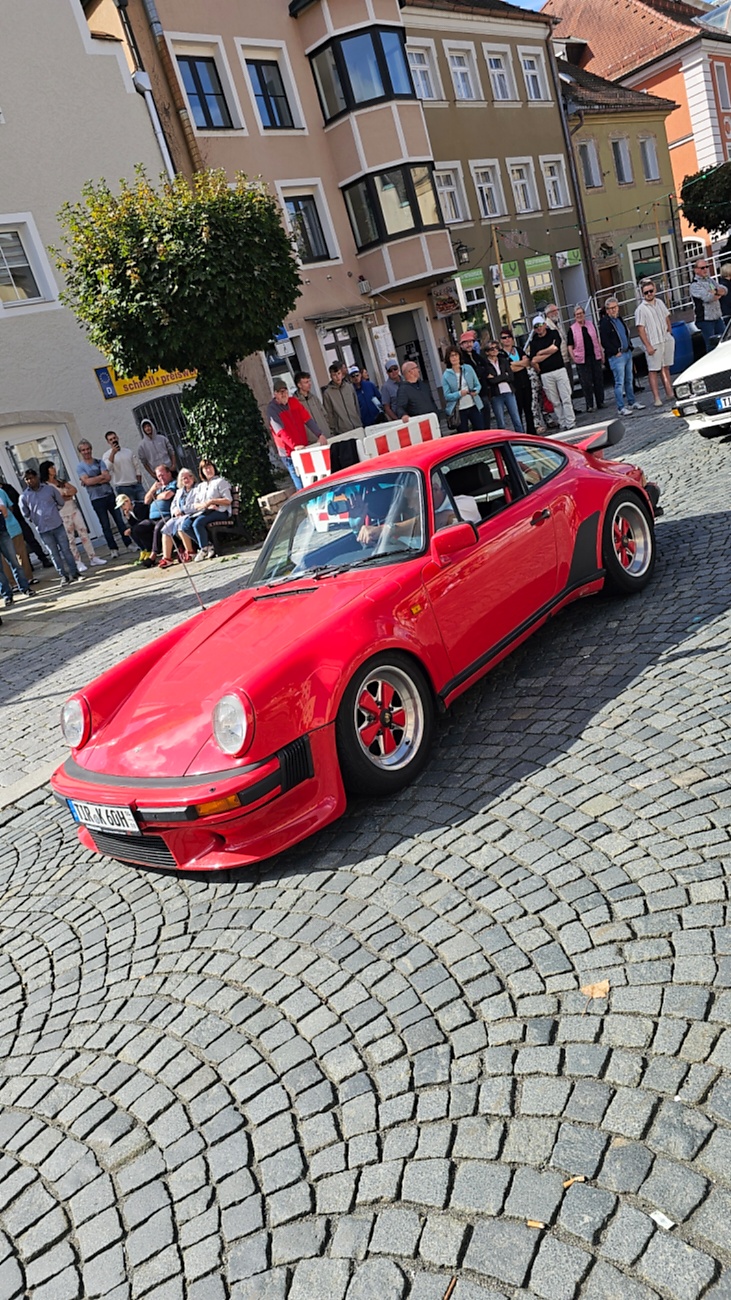 Jede Menge automobile Schätze auf dem Kemnather Stadtplatz

Ein echtes Paradies für Oldtimerfreunde gab es am Samstag beim großen Oldtimertreffen in Kemnath zu erleben. Ab 10 Uhr gehörte der wunderschöne historische Stadtplatz den automobilen Schätzen vergangener Jahrzehnte. Bei bestem Oldtimerwetter präsentierten sich die liebevoll gepflegten Fahrzeuge vor einer traumhaften Kulisse – und natürlich ließen sich das auch jede Menge Zuschauer nicht entgehen.

Dicht an dicht standen die Besucher entlang des Stadtplatzes, als ein Klassiker nach dem anderen zur Fahrzeugvorstellung vorfuhr. Dabei gab es nicht nur jede Menge Chrom, glänzenden Lack und den unverwechselbaren Klang alter Motoren zu bestaunen, sondern auch viel Wissenswertes zu hören.

Wie jedes Jahr hatte Elmar Högl das Mikrofon fest im Griff. Souverän und mit enormem Fachwissen stellte er die einzelnen Fahrzeuge vor, erzählte von Baujahren, Motorisierung und technischen Besonderheiten und hatte dabei immer wieder interessante Details zu den Oldtimern parat.

Und eigentlich ist Elmar Högl aus dem Kemnather Oldtimertreffen kaum wegzudenken. Er ist nicht nur die bekannte Stimme am Mikrofon, sondern zugleich Hauptorganisator und so etwas wie das „Herz“ des Treffens. Gemeinsam mit dem KEM-Verband und der Stadt Kemnath sorgt er dafür, dass die Freunde historischer Fahrzeuge Jahr für Jahr in Kemnath zusammenkommen.

Zur Fahrzeugvorstellung gehörte natürlich auch die Übergabe der Urkunden. Diese Aufgabe übernahm Hermann Schraml, unterstützt von Stefan Wöhrl.

Und besser hätte es an diesem Vormittag eigentlich kaum passen können: herrliches Wetter, ein voller Stadtplatz, viele begeisterte Zuschauer und mittendrin jede Menge automobile Zeitgeschichte auf zwei und vier Rädern.

Nach der Vorstellung blieb noch genügend Zeit, die Oldtimer aus nächster Nähe zu betrachten, mit den Besitzern ins Gespräch zu kommen und natürlich jede Menge Fotos zu machen.

Am Nachmittag wartete dann bereits der nächste Höhepunkt auf die Teilnehmer. Um 13:15 Uhr machten sich die historischen Fahrzeuge zur gemeinsamen Ausfahrt auf den Weg. Über Berndorf, Haidenaab und Weidenberg führte die Tour unter anderem nach Goldkronach, wo eine längere Rast eingelegt wurde, bevor es schließlich wieder zurück nach Kemnath ging.

Und jetzt viel Spaß beim Durchklicken durch unsere Bilder vom Kemnather Oldtimertreffen 2026!