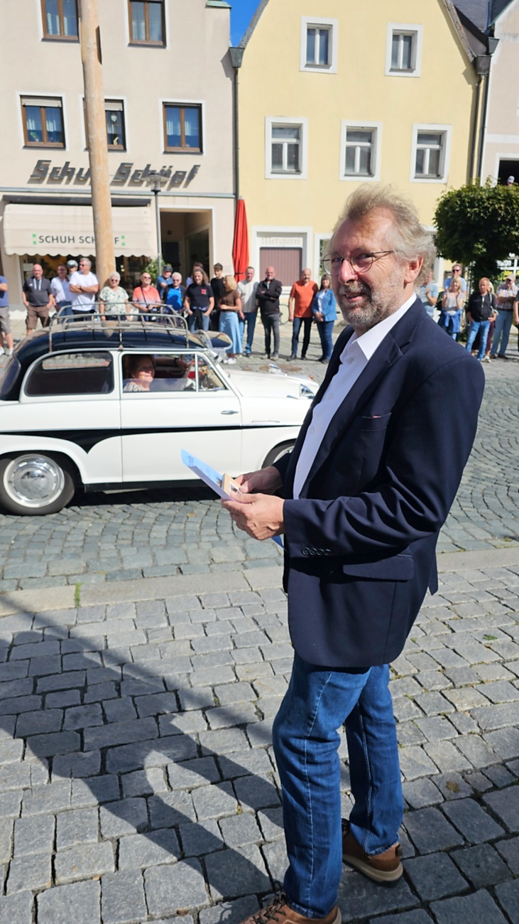 Jede Menge automobile Schätze auf dem Kemnather Stadtplatz

Ein echtes Paradies für Oldtimerfreunde gab es am Samstag beim großen Oldtimertreffen in Kemnath zu erleben. Ab 10 Uhr gehörte der wunderschöne historische Stadtplatz den automobilen Schätzen vergangener Jahrzehnte. Bei bestem Oldtimerwetter präsentierten sich die liebevoll gepflegten Fahrzeuge vor einer traumhaften Kulisse – und natürlich ließen sich das auch jede Menge Zuschauer nicht entgehen.

Dicht an dicht standen die Besucher entlang des Stadtplatzes, als ein Klassiker nach dem anderen zur Fahrzeugvorstellung vorfuhr. Dabei gab es nicht nur jede Menge Chrom, glänzenden Lack und den unverwechselbaren Klang alter Motoren zu bestaunen, sondern auch viel Wissenswertes zu hören.

Wie jedes Jahr hatte Elmar Högl das Mikrofon fest im Griff. Souverän und mit enormem Fachwissen stellte er die einzelnen Fahrzeuge vor, erzählte von Baujahren, Motorisierung und technischen Besonderheiten und hatte dabei immer wieder interessante Details zu den Oldtimern parat.

Und eigentlich ist Elmar Högl aus dem Kemnather Oldtimertreffen kaum wegzudenken. Er ist nicht nur die bekannte Stimme am Mikrofon, sondern zugleich Hauptorganisator und so etwas wie das „Herz“ des Treffens. Gemeinsam mit dem KEM-Verband und der Stadt Kemnath sorgt er dafür, dass die Freunde historischer Fahrzeuge Jahr für Jahr in Kemnath zusammenkommen.

Zur Fahrzeugvorstellung gehörte natürlich auch die Übergabe der Urkunden. Diese Aufgabe übernahm Hermann Schraml, unterstützt von Stefan Wöhrl.

Und besser hätte es an diesem Vormittag eigentlich kaum passen können: herrliches Wetter, ein voller Stadtplatz, viele begeisterte Zuschauer und mittendrin jede Menge automobile Zeitgeschichte auf zwei und vier Rädern.

Nach der Vorstellung blieb noch genügend Zeit, die Oldtimer aus nächster Nähe zu betrachten, mit den Besitzern ins Gespräch zu kommen und natürlich jede Menge Fotos zu machen.

Am Nachmittag wartete dann bereits der nächste Höhepunkt auf die Teilnehmer. Um 13:15 Uhr machten sich die historischen Fahrzeuge zur gemeinsamen Ausfahrt auf den Weg. Über Berndorf, Haidenaab und Weidenberg führte die Tour unter anderem nach Goldkronach, wo eine längere Rast eingelegt wurde, bevor es schließlich wieder zurück nach Kemnath ging.

Und jetzt viel Spaß beim Durchklicken durch unsere Bilder vom Kemnather Oldtimertreffen 2026!