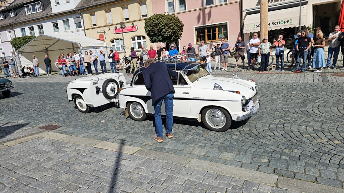 Jede Menge automobile Schätze auf dem Kemnather Stadtplatz

Ein echtes Paradies für Oldtimerfreunde gab es am Samstag beim großen Oldtimertreffen in Kemnath zu erleben. Ab 10 Uhr gehörte der wunderschöne historische Stadtplatz den automobilen Schätzen vergangener Jahrzehnte. Bei bestem Oldtimerwetter präsentierten sich die liebevoll gepflegten Fahrzeuge vor einer traumhaften Kulisse – und natürlich ließen sich das auch jede Menge Zuschauer nicht entgehen.

Dicht an dicht standen die Besucher entlang des Stadtplatzes, als ein Klassiker nach dem anderen zur Fahrzeugvorstellung vorfuhr. Dabei gab es nicht nur jede Menge Chrom, glänzenden Lack und den unverwechselbaren Klang alter Motoren zu bestaunen, sondern auch viel Wissenswertes zu hören.

Wie jedes Jahr hatte Elmar Högl das Mikrofon fest im Griff. Souverän und mit enormem Fachwissen stellte er die einzelnen Fahrzeuge vor, erzählte von Baujahren, Motorisierung und technischen Besonderheiten und hatte dabei immer wieder interessante Details zu den Oldtimern parat.

Und eigentlich ist Elmar Högl aus dem Kemnather Oldtimertreffen kaum wegzudenken. Er ist nicht nur die bekannte Stimme am Mikrofon, sondern zugleich Hauptorganisator und so etwas wie das „Herz“ des Treffens. Gemeinsam mit dem KEM-Verband und der Stadt Kemnath sorgt er dafür, dass die Freunde historischer Fahrzeuge Jahr für Jahr in Kemnath zusammenkommen.

Zur Fahrzeugvorstellung gehörte natürlich auch die Übergabe der Urkunden. Diese Aufgabe übernahm Hermann Schraml, unterstützt von Stefan Wöhrl.

Und besser hätte es an diesem Vormittag eigentlich kaum passen können: herrliches Wetter, ein voller Stadtplatz, viele begeisterte Zuschauer und mittendrin jede Menge automobile Zeitgeschichte auf zwei und vier Rädern.

Nach der Vorstellung blieb noch genügend Zeit, die Oldtimer aus nächster Nähe zu betrachten, mit den Besitzern ins Gespräch zu kommen und natürlich jede Menge Fotos zu machen.

Am Nachmittag wartete dann bereits der nächste Höhepunkt auf die Teilnehmer. Um 13:15 Uhr machten sich die historischen Fahrzeuge zur gemeinsamen Ausfahrt auf den Weg. Über Berndorf, Haidenaab und Weidenberg führte die Tour unter anderem nach Goldkronach, wo eine längere Rast eingelegt wurde, bevor es schließlich wieder zurück nach Kemnath ging.

Und jetzt viel Spaß beim Durchklicken durch unsere Bilder vom Kemnather Oldtimertreffen 2026!