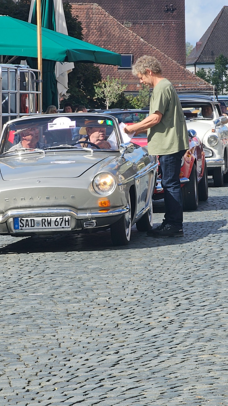Jede Menge automobile Schätze auf dem Kemnather Stadtplatz

Ein echtes Paradies für Oldtimerfreunde gab es am Samstag beim großen Oldtimertreffen in Kemnath zu erleben. Ab 10 Uhr gehörte der wunderschöne historische Stadtplatz den automobilen Schätzen vergangener Jahrzehnte. Bei bestem Oldtimerwetter präsentierten sich die liebevoll gepflegten Fahrzeuge vor einer traumhaften Kulisse – und natürlich ließen sich das auch jede Menge Zuschauer nicht entgehen.

Dicht an dicht standen die Besucher entlang des Stadtplatzes, als ein Klassiker nach dem anderen zur Fahrzeugvorstellung vorfuhr. Dabei gab es nicht nur jede Menge Chrom, glänzenden Lack und den unverwechselbaren Klang alter Motoren zu bestaunen, sondern auch viel Wissenswertes zu hören.

Wie jedes Jahr hatte Elmar Högl das Mikrofon fest im Griff. Souverän und mit enormem Fachwissen stellte er die einzelnen Fahrzeuge vor, erzählte von Baujahren, Motorisierung und technischen Besonderheiten und hatte dabei immer wieder interessante Details zu den Oldtimern parat.

Und eigentlich ist Elmar Högl aus dem Kemnather Oldtimertreffen kaum wegzudenken. Er ist nicht nur die bekannte Stimme am Mikrofon, sondern zugleich Hauptorganisator und so etwas wie das „Herz“ des Treffens. Gemeinsam mit dem KEM-Verband und der Stadt Kemnath sorgt er dafür, dass die Freunde historischer Fahrzeuge Jahr für Jahr in Kemnath zusammenkommen.

Zur Fahrzeugvorstellung gehörte natürlich auch die Übergabe der Urkunden. Diese Aufgabe übernahm Hermann Schraml, unterstützt von Stefan Wöhrl.

Und besser hätte es an diesem Vormittag eigentlich kaum passen können: herrliches Wetter, ein voller Stadtplatz, viele begeisterte Zuschauer und mittendrin jede Menge automobile Zeitgeschichte auf zwei und vier Rädern.

Nach der Vorstellung blieb noch genügend Zeit, die Oldtimer aus nächster Nähe zu betrachten, mit den Besitzern ins Gespräch zu kommen und natürlich jede Menge Fotos zu machen.

Am Nachmittag wartete dann bereits der nächste Höhepunkt auf die Teilnehmer. Um 13:15 Uhr machten sich die historischen Fahrzeuge zur gemeinsamen Ausfahrt auf den Weg. Über Berndorf, Haidenaab und Weidenberg führte die Tour unter anderem nach Goldkronach, wo eine längere Rast eingelegt wurde, bevor es schließlich wieder zurück nach Kemnath ging.

Und jetzt viel Spaß beim Durchklicken durch unsere Bilder vom Kemnather Oldtimertreffen 2026!
