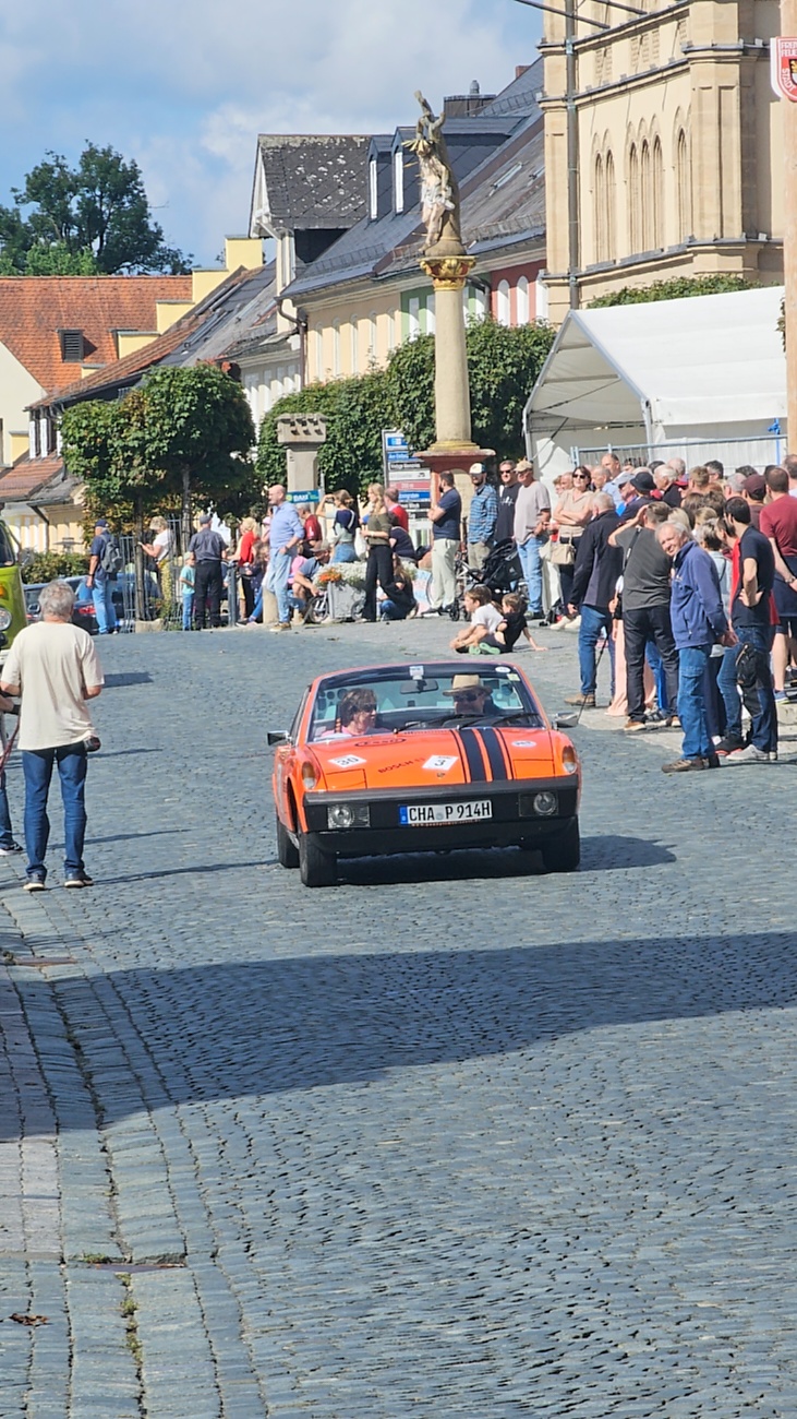 Jede Menge automobile Schätze auf dem Kemnather Stadtplatz

Ein echtes Paradies für Oldtimerfreunde gab es am Samstag beim großen Oldtimertreffen in Kemnath zu erleben. Ab 10 Uhr gehörte der wunderschöne historische Stadtplatz den automobilen Schätzen vergangener Jahrzehnte. Bei bestem Oldtimerwetter präsentierten sich die liebevoll gepflegten Fahrzeuge vor einer traumhaften Kulisse – und natürlich ließen sich das auch jede Menge Zuschauer nicht entgehen.

Dicht an dicht standen die Besucher entlang des Stadtplatzes, als ein Klassiker nach dem anderen zur Fahrzeugvorstellung vorfuhr. Dabei gab es nicht nur jede Menge Chrom, glänzenden Lack und den unverwechselbaren Klang alter Motoren zu bestaunen, sondern auch viel Wissenswertes zu hören.

Wie jedes Jahr hatte Elmar Högl das Mikrofon fest im Griff. Souverän und mit enormem Fachwissen stellte er die einzelnen Fahrzeuge vor, erzählte von Baujahren, Motorisierung und technischen Besonderheiten und hatte dabei immer wieder interessante Details zu den Oldtimern parat.

Und eigentlich ist Elmar Högl aus dem Kemnather Oldtimertreffen kaum wegzudenken. Er ist nicht nur die bekannte Stimme am Mikrofon, sondern zugleich Hauptorganisator und so etwas wie das „Herz“ des Treffens. Gemeinsam mit dem KEM-Verband und der Stadt Kemnath sorgt er dafür, dass die Freunde historischer Fahrzeuge Jahr für Jahr in Kemnath zusammenkommen.

Zur Fahrzeugvorstellung gehörte natürlich auch die Übergabe der Urkunden. Diese Aufgabe übernahm Hermann Schraml, unterstützt von Stefan Wöhrl.

Und besser hätte es an diesem Vormittag eigentlich kaum passen können: herrliches Wetter, ein voller Stadtplatz, viele begeisterte Zuschauer und mittendrin jede Menge automobile Zeitgeschichte auf zwei und vier Rädern.

Nach der Vorstellung blieb noch genügend Zeit, die Oldtimer aus nächster Nähe zu betrachten, mit den Besitzern ins Gespräch zu kommen und natürlich jede Menge Fotos zu machen.

Am Nachmittag wartete dann bereits der nächste Höhepunkt auf die Teilnehmer. Um 13:15 Uhr machten sich die historischen Fahrzeuge zur gemeinsamen Ausfahrt auf den Weg. Über Berndorf, Haidenaab und Weidenberg führte die Tour unter anderem nach Goldkronach, wo eine längere Rast eingelegt wurde, bevor es schließlich wieder zurück nach Kemnath ging.

Und jetzt viel Spaß beim Durchklicken durch unsere Bilder vom Kemnather Oldtimertreffen 2026!