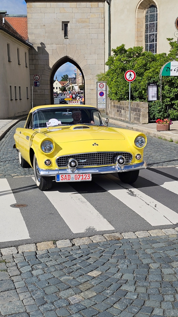 Jede Menge automobile Schätze auf dem Kemnather Stadtplatz

Ein echtes Paradies für Oldtimerfreunde gab es am Samstag beim großen Oldtimertreffen in Kemnath zu erleben. Ab 10 Uhr gehörte der wunderschöne historische Stadtplatz den automobilen Schätzen vergangener Jahrzehnte. Bei bestem Oldtimerwetter präsentierten sich die liebevoll gepflegten Fahrzeuge vor einer traumhaften Kulisse – und natürlich ließen sich das auch jede Menge Zuschauer nicht entgehen.

Dicht an dicht standen die Besucher entlang des Stadtplatzes, als ein Klassiker nach dem anderen zur Fahrzeugvorstellung vorfuhr. Dabei gab es nicht nur jede Menge Chrom, glänzenden Lack und den unverwechselbaren Klang alter Motoren zu bestaunen, sondern auch viel Wissenswertes zu hören.

Wie jedes Jahr hatte Elmar Högl das Mikrofon fest im Griff. Souverän und mit enormem Fachwissen stellte er die einzelnen Fahrzeuge vor, erzählte von Baujahren, Motorisierung und technischen Besonderheiten und hatte dabei immer wieder interessante Details zu den Oldtimern parat.

Und eigentlich ist Elmar Högl aus dem Kemnather Oldtimertreffen kaum wegzudenken. Er ist nicht nur die bekannte Stimme am Mikrofon, sondern zugleich Hauptorganisator und so etwas wie das „Herz“ des Treffens. Gemeinsam mit dem KEM-Verband und der Stadt Kemnath sorgt er dafür, dass die Freunde historischer Fahrzeuge Jahr für Jahr in Kemnath zusammenkommen.

Zur Fahrzeugvorstellung gehörte natürlich auch die Übergabe der Urkunden. Diese Aufgabe übernahm Hermann Schraml, unterstützt von Stefan Wöhrl.

Und besser hätte es an diesem Vormittag eigentlich kaum passen können: herrliches Wetter, ein voller Stadtplatz, viele begeisterte Zuschauer und mittendrin jede Menge automobile Zeitgeschichte auf zwei und vier Rädern.

Nach der Vorstellung blieb noch genügend Zeit, die Oldtimer aus nächster Nähe zu betrachten, mit den Besitzern ins Gespräch zu kommen und natürlich jede Menge Fotos zu machen.

Am Nachmittag wartete dann bereits der nächste Höhepunkt auf die Teilnehmer. Um 13:15 Uhr machten sich die historischen Fahrzeuge zur gemeinsamen Ausfahrt auf den Weg. Über Berndorf, Haidenaab und Weidenberg führte die Tour unter anderem nach Goldkronach, wo eine längere Rast eingelegt wurde, bevor es schließlich wieder zurück nach Kemnath ging.

Und jetzt viel Spaß beim Durchklicken durch unsere Bilder vom Kemnather Oldtimertreffen 2026!