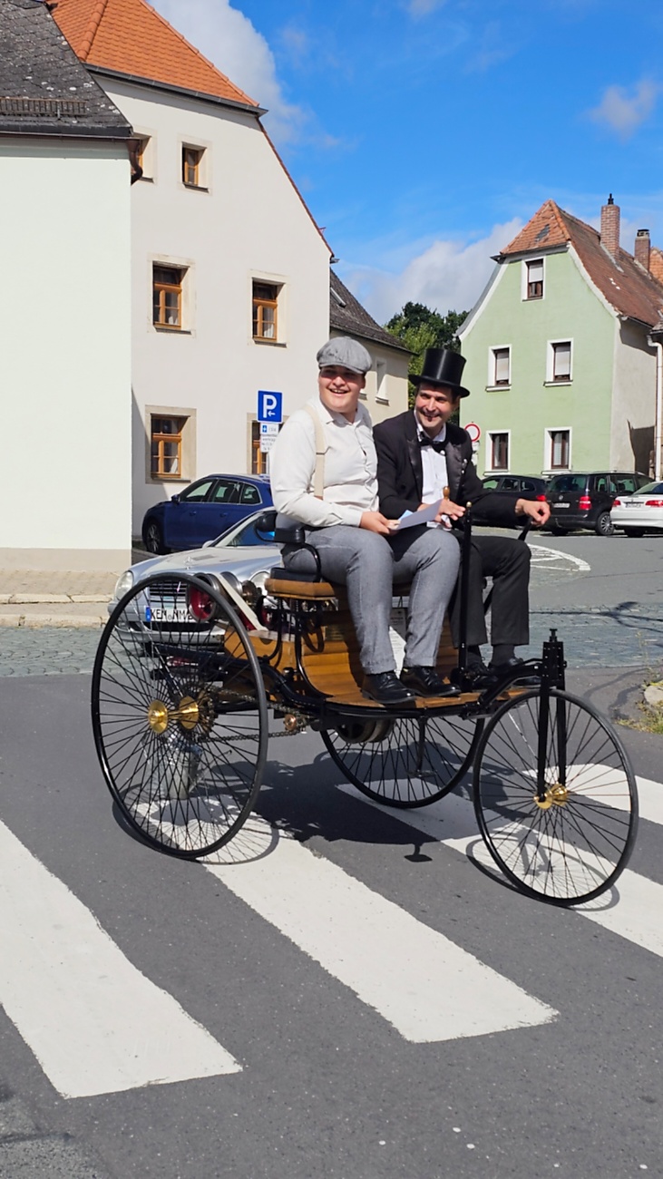 Jede Menge automobile Schätze auf dem Kemnather Stadtplatz

Ein echtes Paradies für Oldtimerfreunde gab es am Samstag beim großen Oldtimertreffen in Kemnath zu erleben. Ab 10 Uhr gehörte der wunderschöne historische Stadtplatz den automobilen Schätzen vergangener Jahrzehnte. Bei bestem Oldtimerwetter präsentierten sich die liebevoll gepflegten Fahrzeuge vor einer traumhaften Kulisse – und natürlich ließen sich das auch jede Menge Zuschauer nicht entgehen.

Dicht an dicht standen die Besucher entlang des Stadtplatzes, als ein Klassiker nach dem anderen zur Fahrzeugvorstellung vorfuhr. Dabei gab es nicht nur jede Menge Chrom, glänzenden Lack und den unverwechselbaren Klang alter Motoren zu bestaunen, sondern auch viel Wissenswertes zu hören.

Wie jedes Jahr hatte Elmar Högl das Mikrofon fest im Griff. Souverän und mit enormem Fachwissen stellte er die einzelnen Fahrzeuge vor, erzählte von Baujahren, Motorisierung und technischen Besonderheiten und hatte dabei immer wieder interessante Details zu den Oldtimern parat.

Und eigentlich ist Elmar Högl aus dem Kemnather Oldtimertreffen kaum wegzudenken. Er ist nicht nur die bekannte Stimme am Mikrofon, sondern zugleich Hauptorganisator und so etwas wie das „Herz“ des Treffens. Gemeinsam mit dem KEM-Verband und der Stadt Kemnath sorgt er dafür, dass die Freunde historischer Fahrzeuge Jahr für Jahr in Kemnath zusammenkommen.

Zur Fahrzeugvorstellung gehörte natürlich auch die Übergabe der Urkunden. Diese Aufgabe übernahm Hermann Schraml, unterstützt von Stefan Wöhrl.

Und besser hätte es an diesem Vormittag eigentlich kaum passen können: herrliches Wetter, ein voller Stadtplatz, viele begeisterte Zuschauer und mittendrin jede Menge automobile Zeitgeschichte auf zwei und vier Rädern.

Nach der Vorstellung blieb noch genügend Zeit, die Oldtimer aus nächster Nähe zu betrachten, mit den Besitzern ins Gespräch zu kommen und natürlich jede Menge Fotos zu machen.

Am Nachmittag wartete dann bereits der nächste Höhepunkt auf die Teilnehmer. Um 13:15 Uhr machten sich die historischen Fahrzeuge zur gemeinsamen Ausfahrt auf den Weg. Über Berndorf, Haidenaab und Weidenberg führte die Tour unter anderem nach Goldkronach, wo eine längere Rast eingelegt wurde, bevor es schließlich wieder zurück nach Kemnath ging.

Und jetzt viel Spaß beim Durchklicken durch unsere Bilder vom Kemnather Oldtimertreffen 2026!
