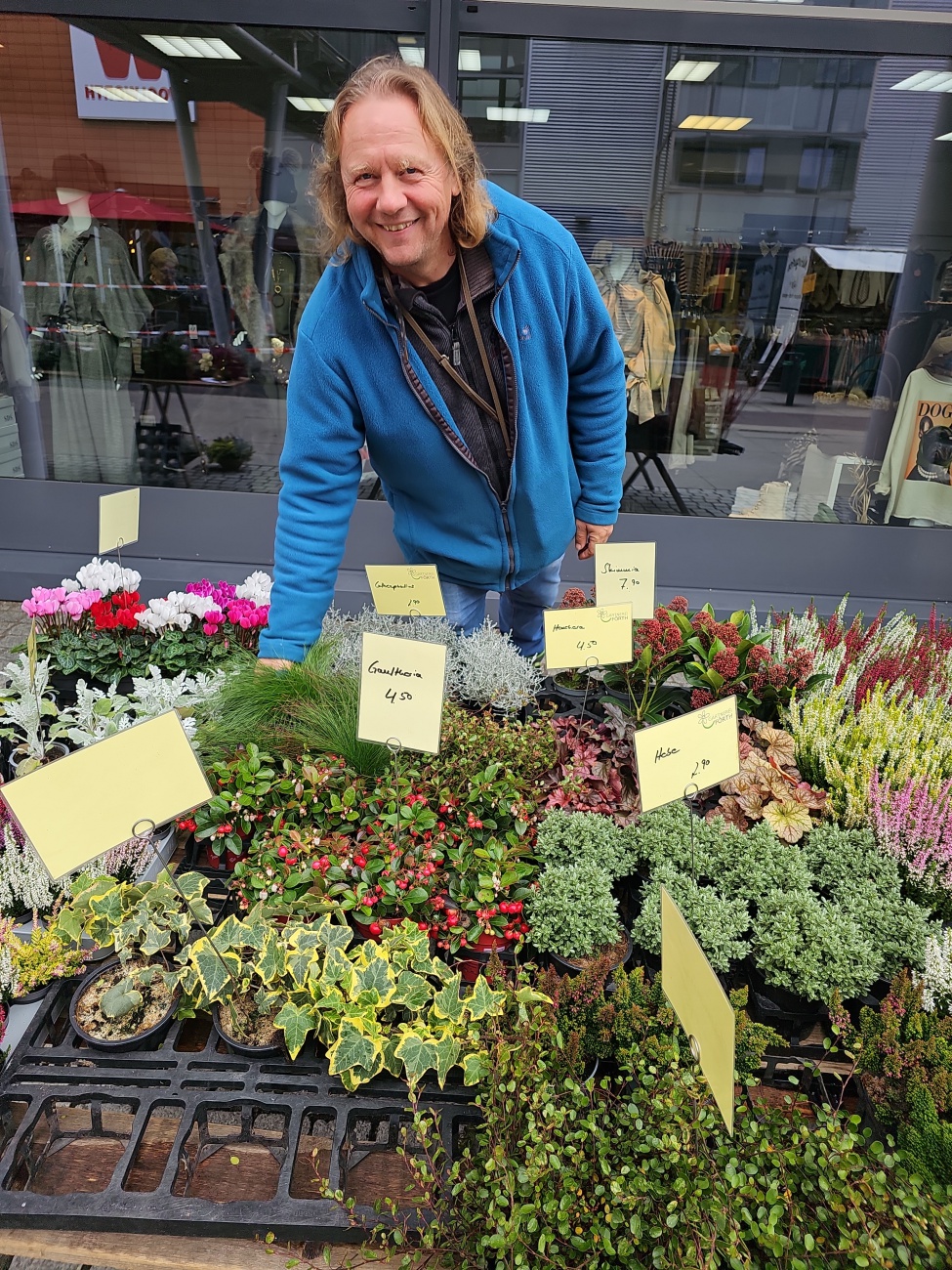 Ein zupackender Marktschreier mit freundlich gelebter Bodenständigkeit: 
Thomas Gruber von der Gärtnerei Förth aus Neusorg breitet auf dem Wochenendmarkt eine bunte Auswahl herbstlicher Pflanzen.

Die handschriftlich beschrifteten Preisschilder mit Logo von "Gärtnerei Förth“ verleihen dem Stand Charme und persönliche Note. 

Der sympathische Blick ins Bild schaffen Nähe und Wärme, ganz wie ein Gespräch unter Nachbarn. 
Wer neugierig wird, kann sich über Tradition und Pflanzenvielfalt der Gärtnerei Förth informieren – ein Zeichen gelebter Verbundenheit zur Region und zur grünen Branche.