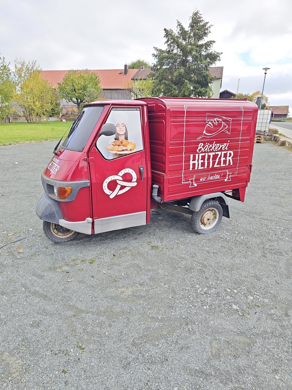 Ein roter Piaggio-Ape mit Brezelsymbol und „Bäckerei Heitzer“-Schriftzug – mobile Tradition auf drei Rädern.
