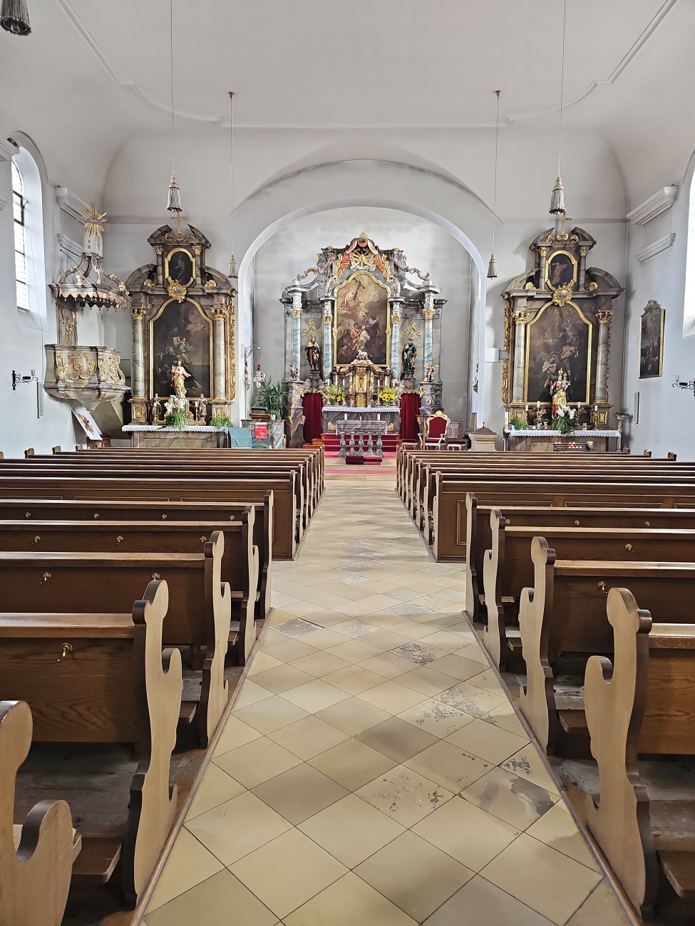 Die Pfarrkirche St. Lucia in Schlammersdorf beeindruckt durch einen schmalen Mittelgang, der auf einen prachtvollen barocken Hochaltar zuführt, flankiert von kunstvoll gestalteten Seitenaltären. Die sandsteinerne Architektur strahlt schlichte Erhabenheit aus.