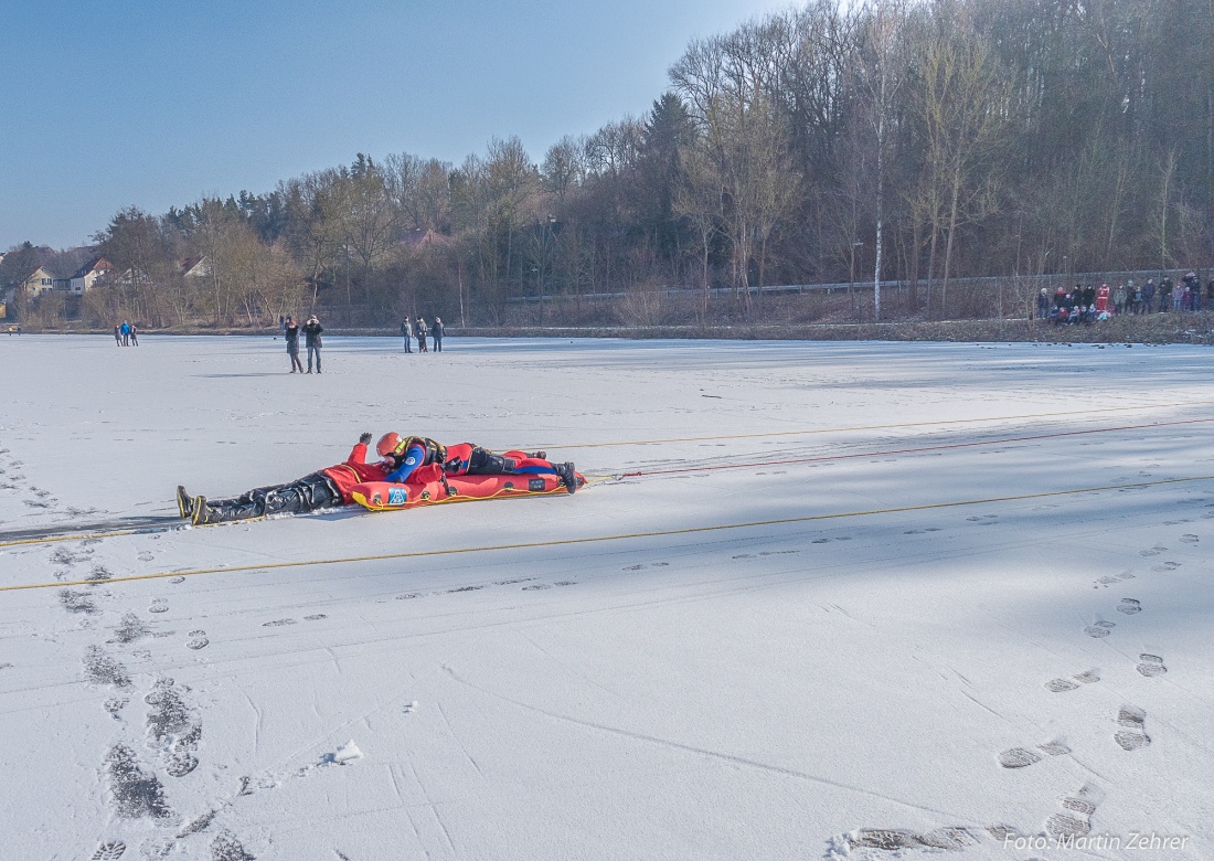 Foto: Martin Zehrer - Teil der Übung... Nachdem der im Eis eingbrochene gerettet aus dem Wasser gezogen wurde, wird er per  Rettungsschlitten zum Ufer gezogen.<br />
Auch Zuschauer verfolgten die R 