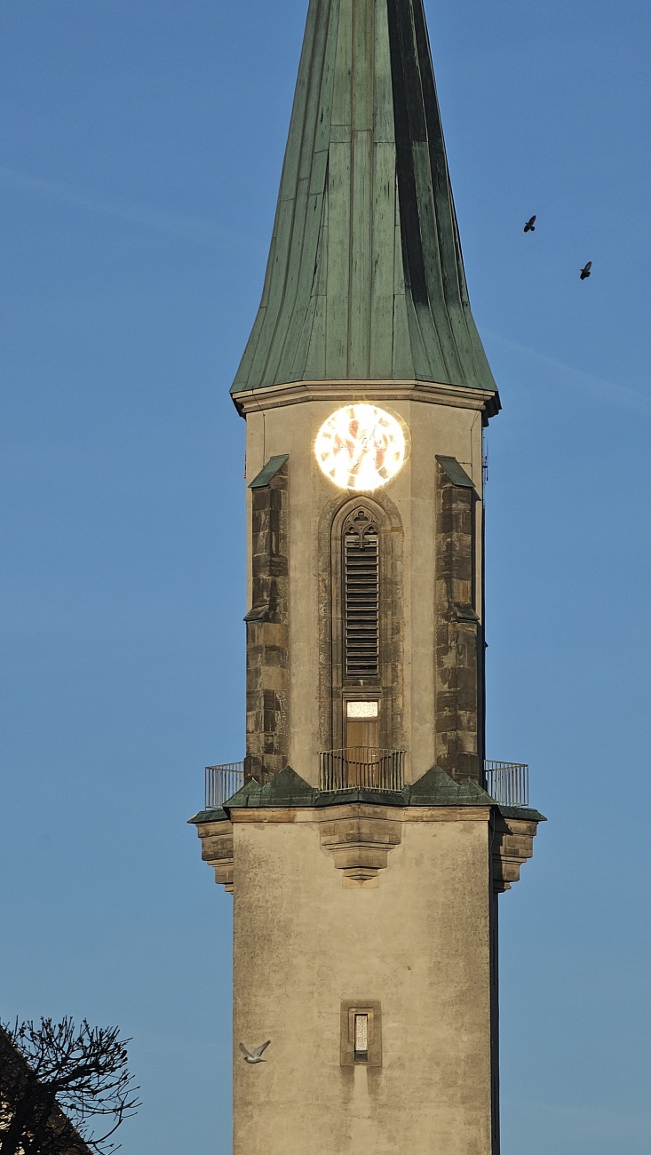 Im warmen Abendlicht, so still und sacht,
hat die Sonne mein Bild zum Leuchten gebracht.
Der Turm von Kemnath, so stolz und so weit,
erzählt von Geschichte und vergangener Zeit.
Erst kürzlich noch hoben Hände mit Bedacht
die Ziffern hinauf in schwindelnde Pracht,
mit Blattgold veredelt, in neuem Glanz,
strahlt nun die Uhr wie ein himmlischer Kranz. 

Was einst verblasste durch Wind und Jahr,
ist nun wieder hell, wie es früher war.
Die Zeiger, die Zahlen - sie tragen nun wieder
den goldenen Schimmer vergangener Lieder.
Und wenn dann die Sonne den Abend küsst,
und still über Dächer und Gassen fließt,
scheint es, als ob aus der Turmeshöh
ein sanftes Strahlen zur Erde geh.
Fast wie ein Herz, das im Himmel erwacht,
leuchtet die Uhr in goldener Pracht.
Ein Gruß an die Menschen, ein Zeichen der Zeit - 
voll Wärme, voll Hoffnung, voll Ewigkeit.