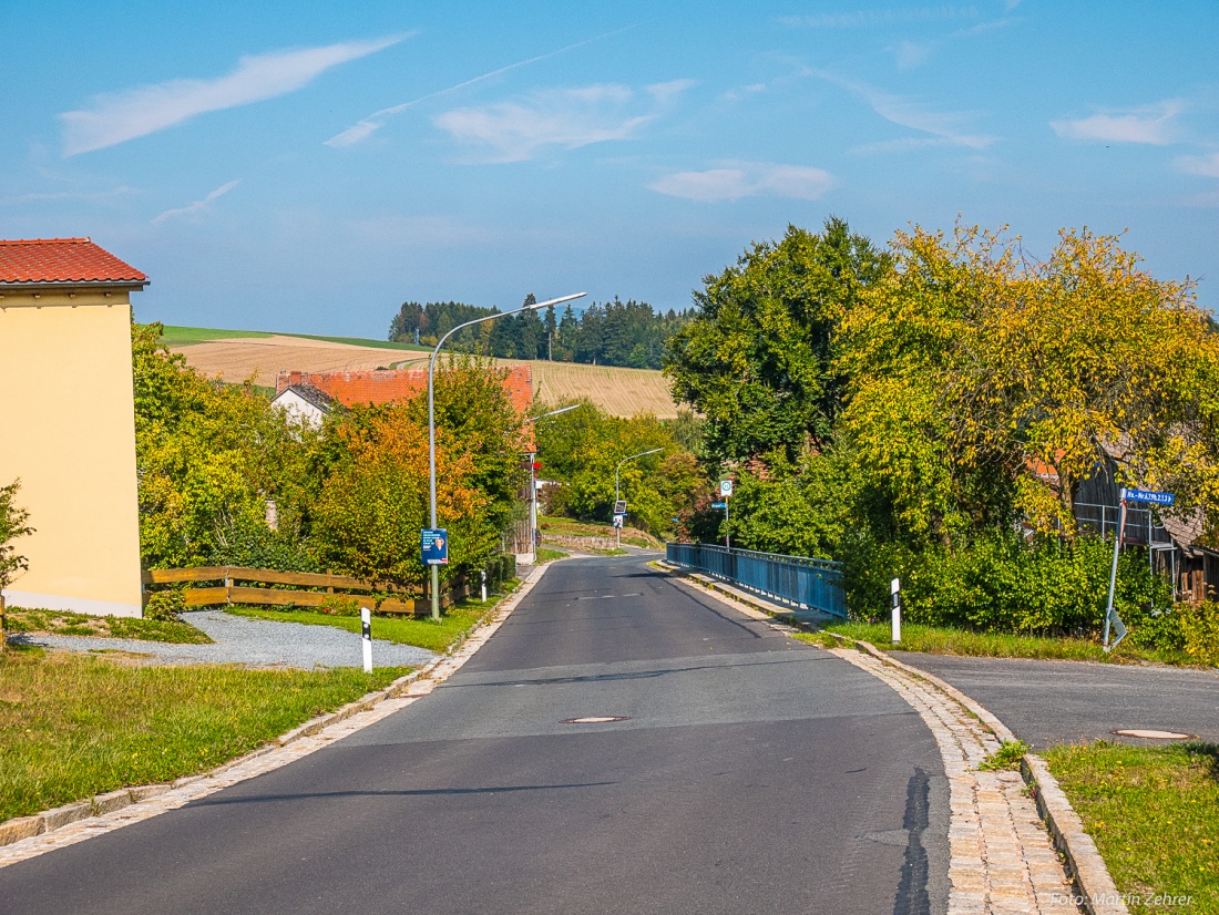 Foto: Martin Zehrer - Die Straße durch Godas. Rechts, dort wo jetzt dieses Eisengeländer am Rand der Straße steht, befand sich früher ein massives Holzgeländer. <br />
Oft saß da die Dorfjugend dra 