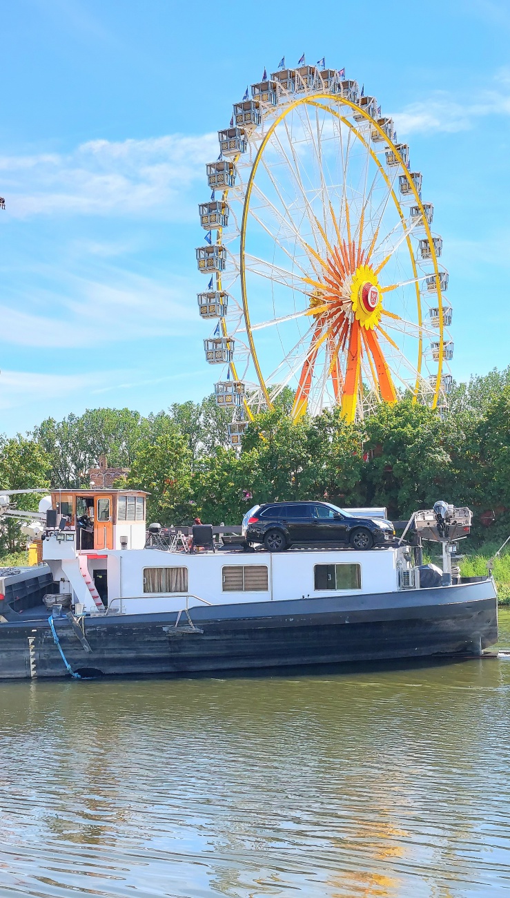 Foto: Martin Zehrer - Im Hintergrund ragt das Riesenrad der Regensburger Dult in den Himmel.<br />
Auf der Donau schippert ein Lastkahn über die Donau... 