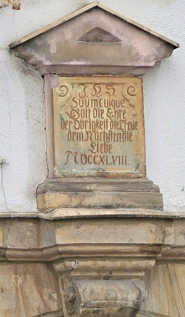 In der Bayreuther Fußgängerzone gefunden...

Der Text ist in alter deutscher Schrift und etwas verblasst, aber er lässt sich ungefähr so lesen:

Gott zu liebe,
Gott die Ehre,
der Obrigkeit die Treue,
dem Nächsten die Liebe.

MDCCXLVIII. = 1748
